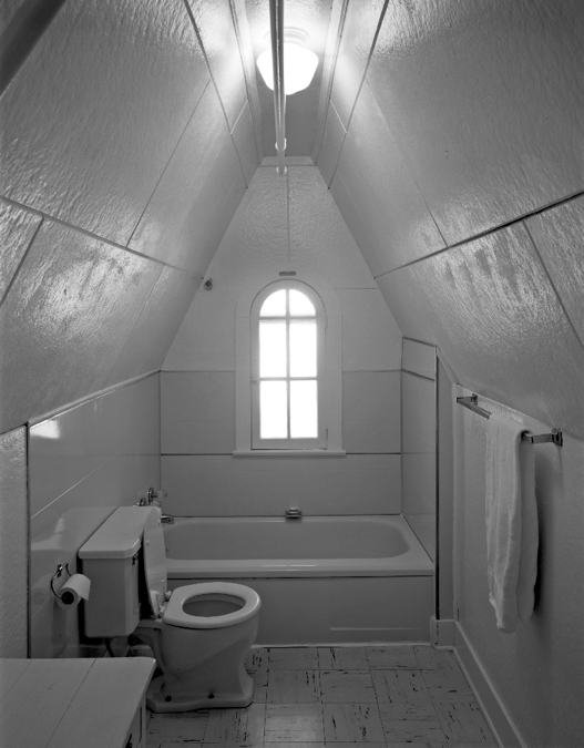 An en-suite bathroom is nestled in a gable dormer in an upper floor guest room.